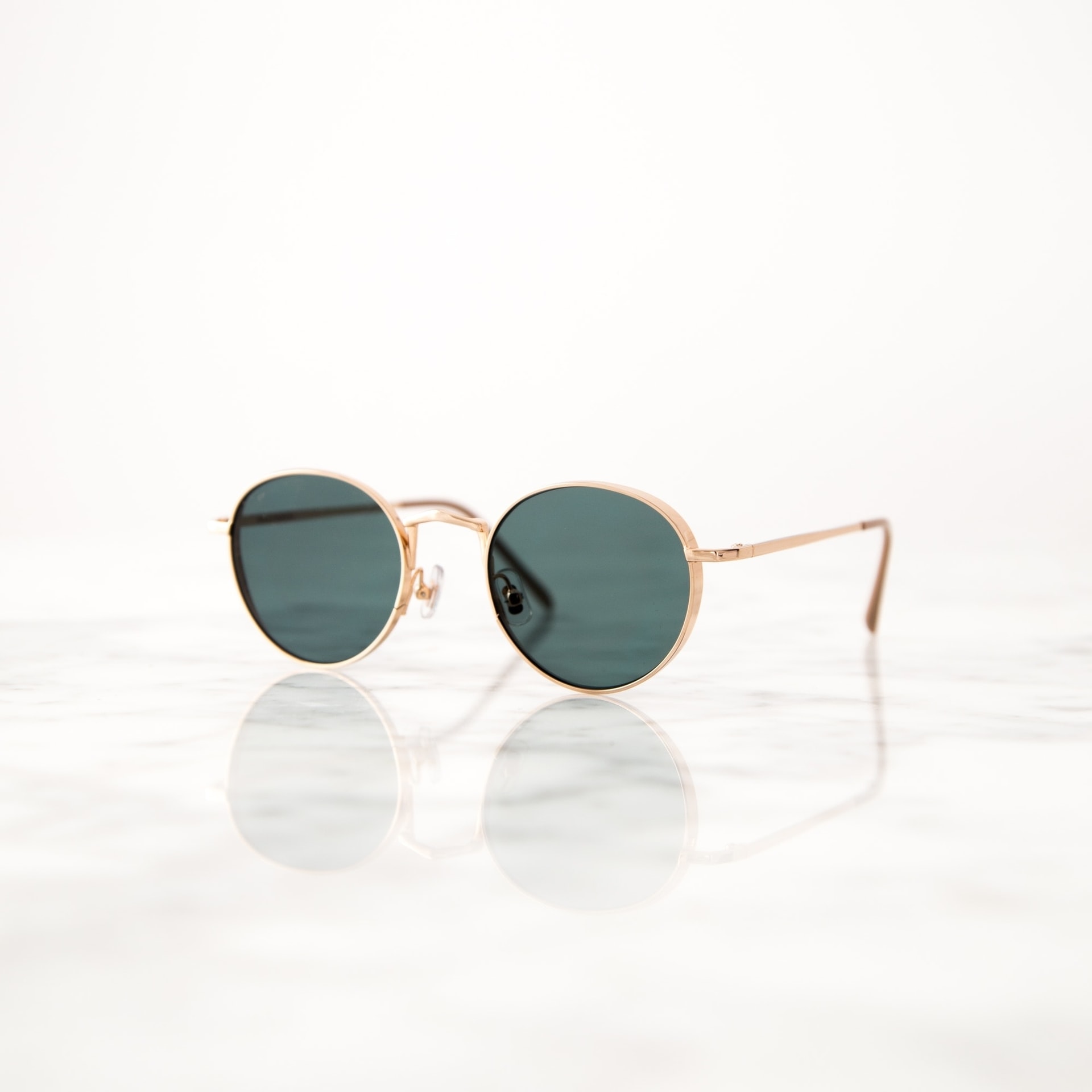 Sonnenbrille Sonnenbrille mit goldenem Gestell auf reflektierendem Marmoruntergrund